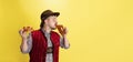 Happy smiling man dressed in traditional Bavarian costume with yummy pretzels isolated over yellow background. National