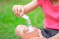 Drink with electrolytes in a transparent bottle in the hands of a happy child on a green lawn in a pink T-shirt