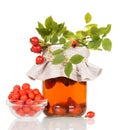 Drink from fruit of rosehip in jar, Rowan berries in bowl isolated on white