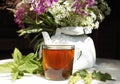 glass cup black tea green leaf berry white kettle table sunlight close-up bouquet flowers Royalty Free Stock Photo