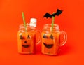 Drink for Halloween. hildren`s and party of Halloween treats. Pumpkin orange cocktail in glasses, decorated with creepy faces