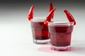 Drink shot prepared with vodka, grenadine and lemon juice decorated with bird eye chillies in the shape of horns