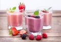Drink smoothies four summer strawberry, blackberry, kiwi, raspberry on wooden table.