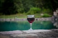 Drink in tall glass in poolside. Refreshment on summer day. Purple juice cocktail or vine. Mountain forest background. Royalty Free Stock Photo