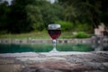 Drink in tall glass in poolside. Refreshment on summer day. Purple juice cocktail or vine. Mountain forest background. Royalty Free Stock Photo