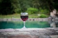 Drink in tall glass in poolside. Refreshment on summer day. Purple juice cocktail or vine. Mountain forest background. Royalty Free Stock Photo