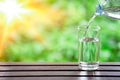 Drink water pouring into glass on wooden table over sunlight with natural lighting and background texture Royalty Free Stock Photo