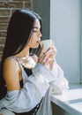 Drink well feel well. Pretty woman drinking healthy morning drink at window. Adorable girl holding cup with tasty coffee Royalty Free Stock Photo