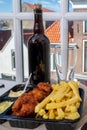 Drinking dark beer with fried cod fish fillet and french fried potatoed chips with view on street in old Zierikzee town, Zeeland,