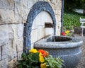 Drinking stone fountain surrounded with flowers. Ladek ZdrÃÂ³j mineral water health resort, Poland.