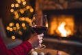 Drinking a glass of red wine in front of fireplace. Relaxing by the fire in cozy living room on winter day. Celebrating Christmas Royalty Free Stock Photo