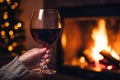 Drinking a glass of red wine in front of fireplace. Relaxing by the fire in cozy living room on winter day. Celebrating Christmas Royalty Free Stock Photo