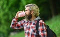 Drinking hot coffee. Enjoying nature at riverside. Guy with backpack relaxing. Inspiration. Inspired handsome hipster Royalty Free Stock Photo