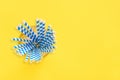 Drinking paper straws for party with blue stripes in glass cup on yellow background with copy space. Top view of colorful paper Royalty Free Stock Photo