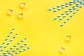 Drinking paper straws for party with blue stripes, ice cube on yellow background with copy space. Top view of colorful paper Royalty Free Stock Photo