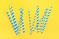Drinking paper straws for party with blue stripes, ice cube on yellow background with copy space. Top view of colorful paper Royalty Free Stock Photo