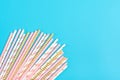 Drinking paper straws for party with golden, white, pastel pink stripes on blue  background Royalty Free Stock Photo