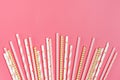 Drinking paper straws for party with golden, white, pink stripes on pink pastel background Royalty Free Stock Photo
