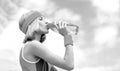 Drinking during sport. Young woman drinking water after run. Woman in sports wear is holding a bottle of water. Sports