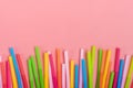 Drinking straws for party in glass on pink pastel background. Top view of colorful plastic tubes for summer cocktails. Royalty Free Stock Photo