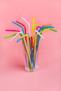 Drinking straws for party in glass on pink pastel background. Top view of colorful plastic tubes for summer cocktails. Royalty Free Stock Photo