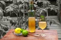 Working from home with limoncello in glass, bottle of sweet Italian lemon liqueur, laim and lemon on the grey background. Royalty Free Stock Photo