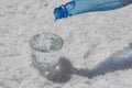 Drinking water from a bottle is poured into a glass cup, the glass stands on large pieces of salt Royalty Free Stock Photo