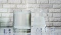 Drinking water in a glass against the background of a white brick wall, ice cubes with a jug of water Royalty Free Stock Photo