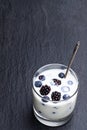 Drinking yogurt with fresh berries in a glass on black stone background