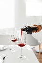 Drinks. Closeup Of Pouring Red Wine From Bottle Into Glass. Royalty Free Stock Photo