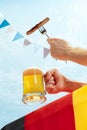 Drinks and snacks. Male hand with glass, mug of cold light beer over light blue sky background. Oktoberfest, vacation Royalty Free Stock Photo