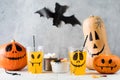 Drinks sweets and pumpkins with frightful faces on table