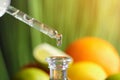 Dripping citrus essential oil into bottle on blurred background