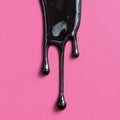 Glossy Black Liquid Dripping on Pink Background Royalty Free Stock Photo