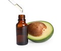 Dripping essential oil into bottle near cut avocado on white background Royalty Free Stock Photo
