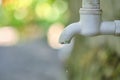 Dripping faucet in white close-up against the background of a green garden Royalty Free Stock Photo