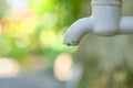 Dripping faucet in white close-up against the background of a green garden Royalty Free Stock Photo