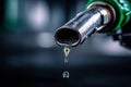 Dripping fuel nozzle with a single drop falling, symbolizing fuel consumption and energy resource concerns in a blurred industrial Royalty Free Stock Photo