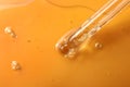 Dripping hydrophilic oil from pipette on orange background, closeup Royalty Free Stock Photo