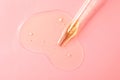 Dripping hydrophilic oil from pipette on pink background, top view