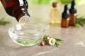 Dripping natural tea tree oil from bottle into bowl on table Royalty Free Stock Photo