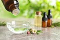 Dripping natural tea tree oil from bottle into bowl on table