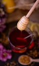 Dripping sweet honey from wooden dipper on cup of tea close-up