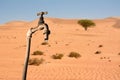 Dripping tap and desert environment in the background Royalty Free Stock Photo