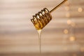 Dripping tasty honey from dipper on blurred background, closeup