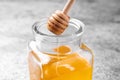 Dripping tasty honey from dipper into glass on table, closeup