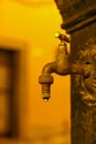 Dripping water from an old tap in the public potable fountain on a blurred background