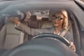 Drive safely. Beautiful business woman in eyeglasses sitting on the front seat of the car and adjusting rear-view mirror Royalty Free Stock Photo