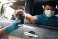 Drive thru food and drink service during Coronavirus COVID-19 pandemic. Staff hand in protective glove serving a coffee cup to