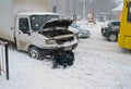 The driver of the car repairs lying in the snow